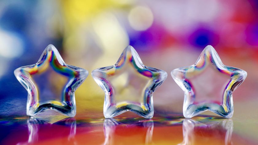 Three small glass stars on a holographic foil background with colourful light effects