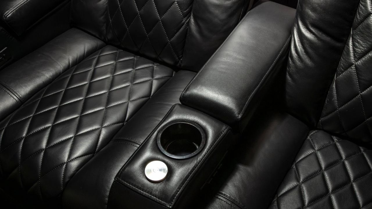 A photo of a custom-installed home cinema room featuring a 4K projector, theatre seating and clever acoustic treatment