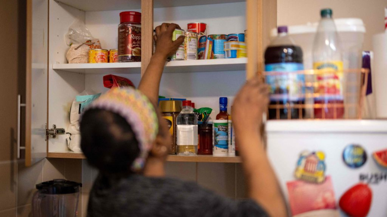 Woman reaches into kitchen cupboards