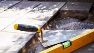 Trowel and spirt level with patio slabs in background