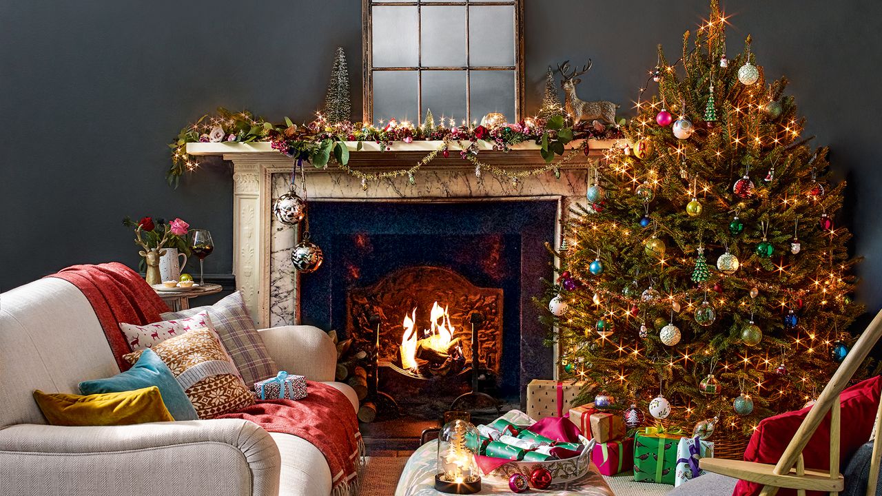 Dark grey living room decorated for Christmas with a style mantlepiece and Christmas tree beside an open fire