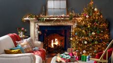 Dark grey living room decorated for Christmas with a style mantlepiece and Christmas tree beside an open fire