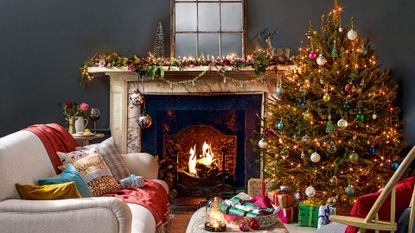 Dark grey living room decorated for Christmas with a style mantlepiece and Christmas tree beside an open fire