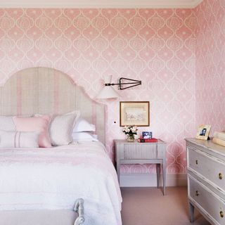 Bedroom with pink wallpaper and striped fabric headboard