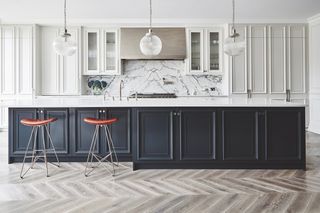 a kitchen with white cabinets and a kitchen island with navy blue cabinets