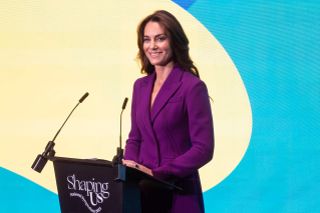 Kate Middleton speaking a podium wearing a purple suit