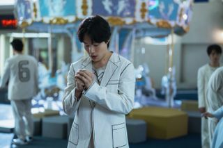 a man (Ryu Jun-yeol) stands in front of a carousel with people scattered around, in the Netflix k-drama 'The 8 Show'