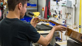 Taylor Guitar factory in Tecate, Mexico. This worker is adjusting the truss rod in the guitar neck
