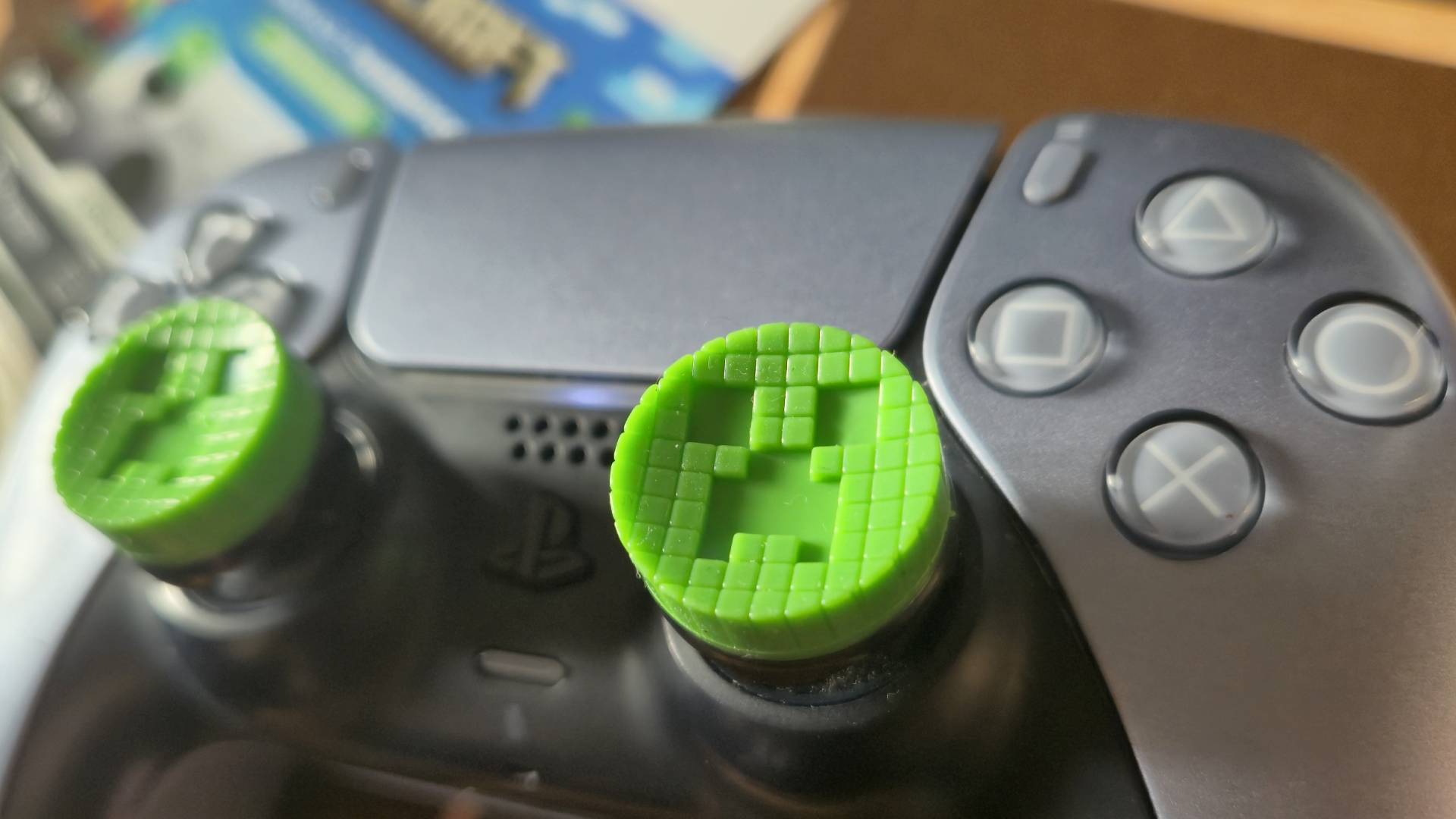 Photo by Rosalie Newcombe of the Minecraft KontrolFreek thumbsticks on a silver PS5 DualSense controller.