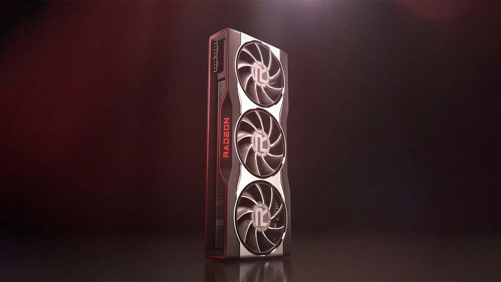 An AMD Radeon graphics card with three fans standing against a dark red background