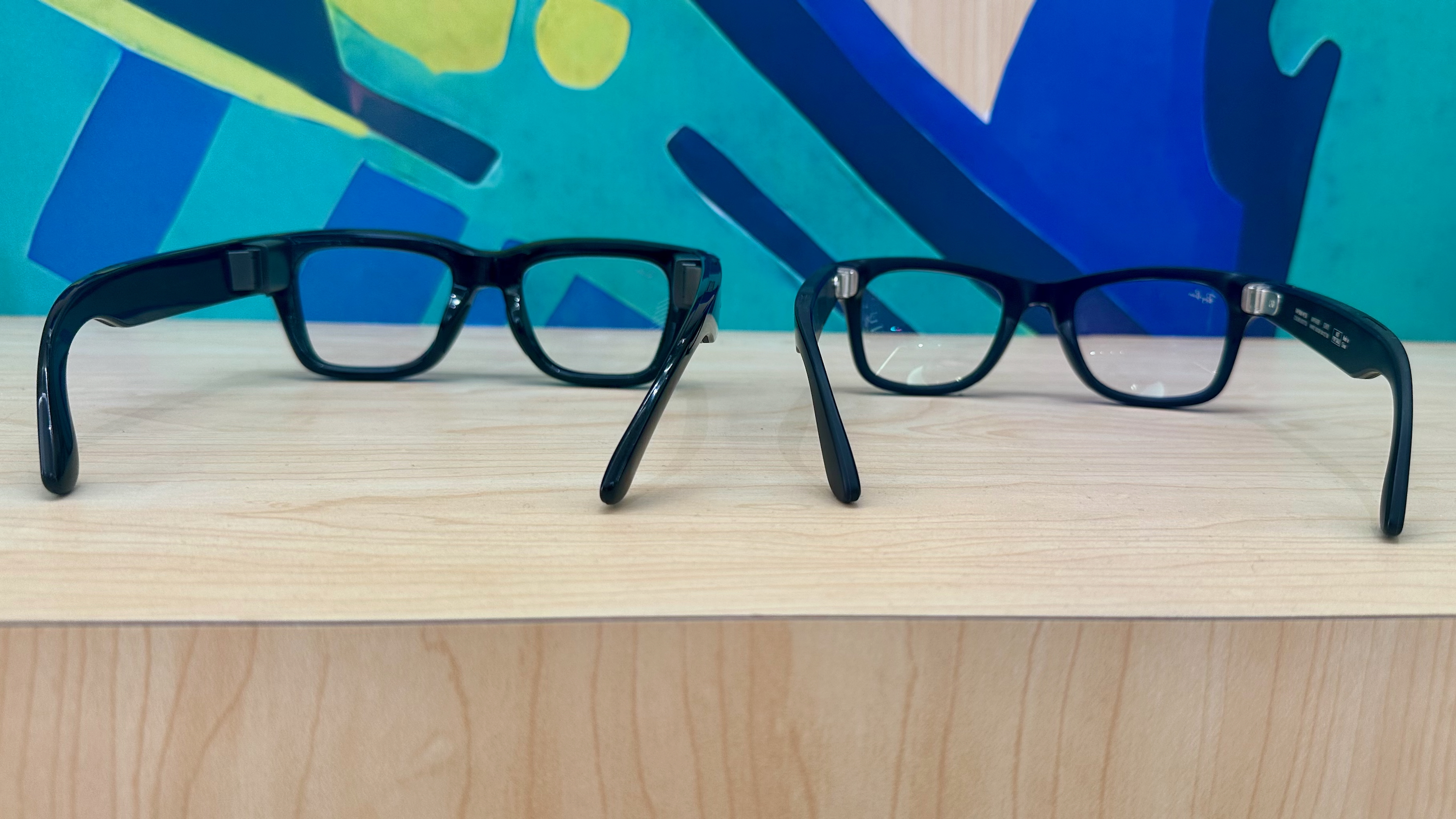 Photo of the Meta Ray-Ban Display (left) and Ray-Ban Meta (Gen 2, right) from the back showing their relative designs.