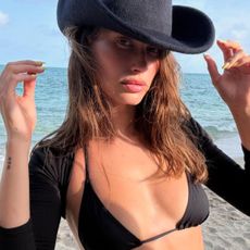 Hailey Bieber on the beach with wavy hair and wearing a cowboy hat