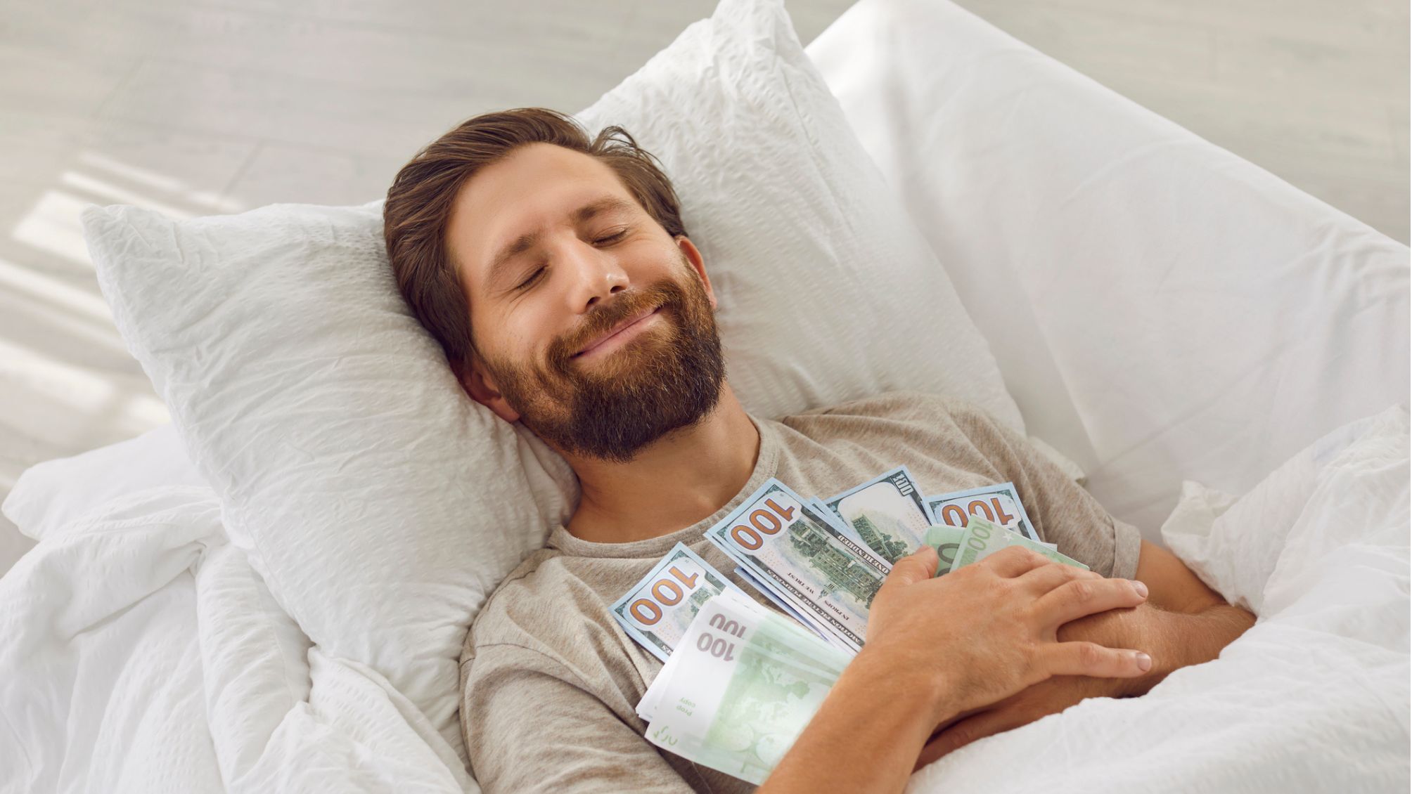 Man sleeping in a bed holding a lot of money 
