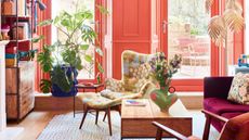 Coral living area with pink, terracotta and lime green seating, industrial wood coffee table and shelving, cobalt blue plant pot and blue and red patterned rug