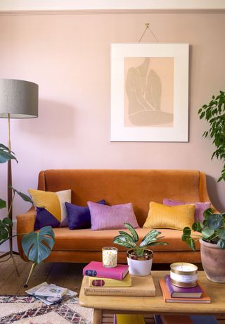 bright living room with an orange sofa, colouful cushions and books on a wooden coffee table