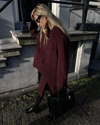 Woman wearing a burgundy skirt suit and sunglasses $ 