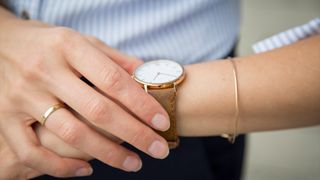 close up on a woman's gold and white wristwatch as she checks it for the time