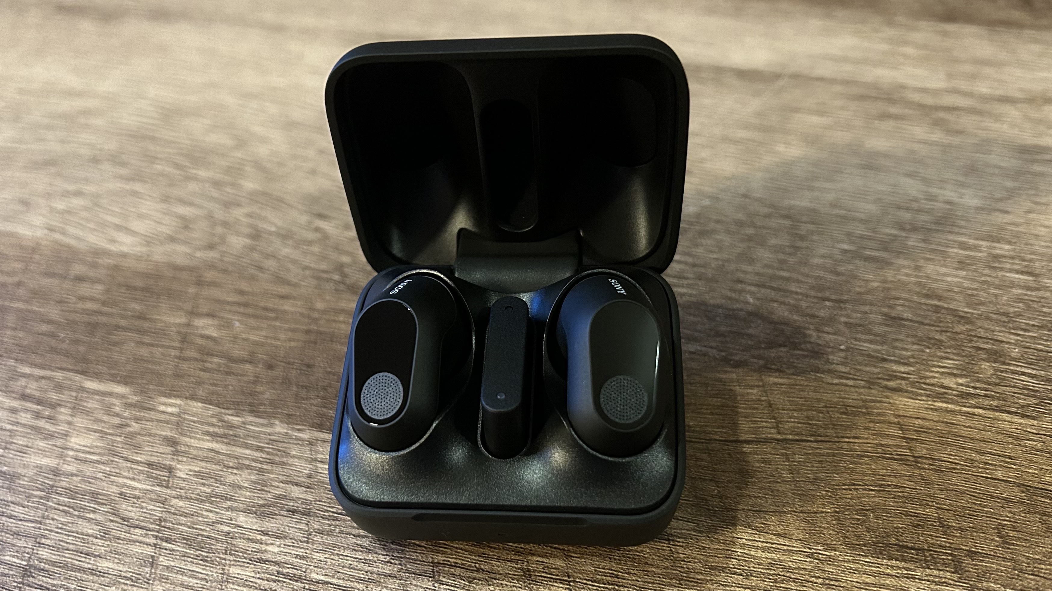 Sony Inzone Buds case open with earbuds inside on a wooden table