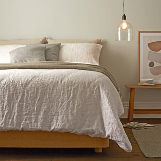 Beige bedding on bed next to side table