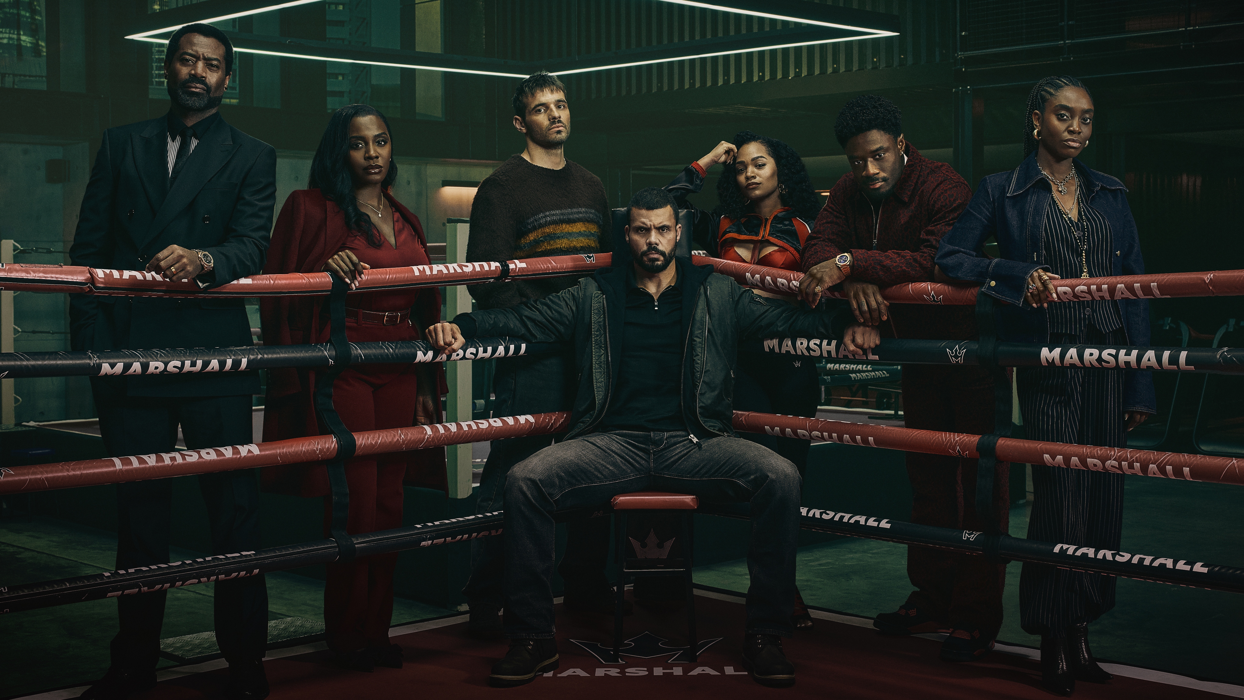 (L-R): Kingsley Marshall, Joy Marshall, Justin "Jay" Hall, Maduka "Duke" Kilroy, Kim Harper, Ezekiel "Zeek" Marshall, and Cebella "Cece" Marshall standing around a boxing ring.