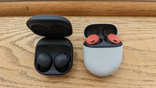 The Samsung Galaxy Buds 2 Pro and Google Pixel Buds Pro sitting side by side on a wooden window sill