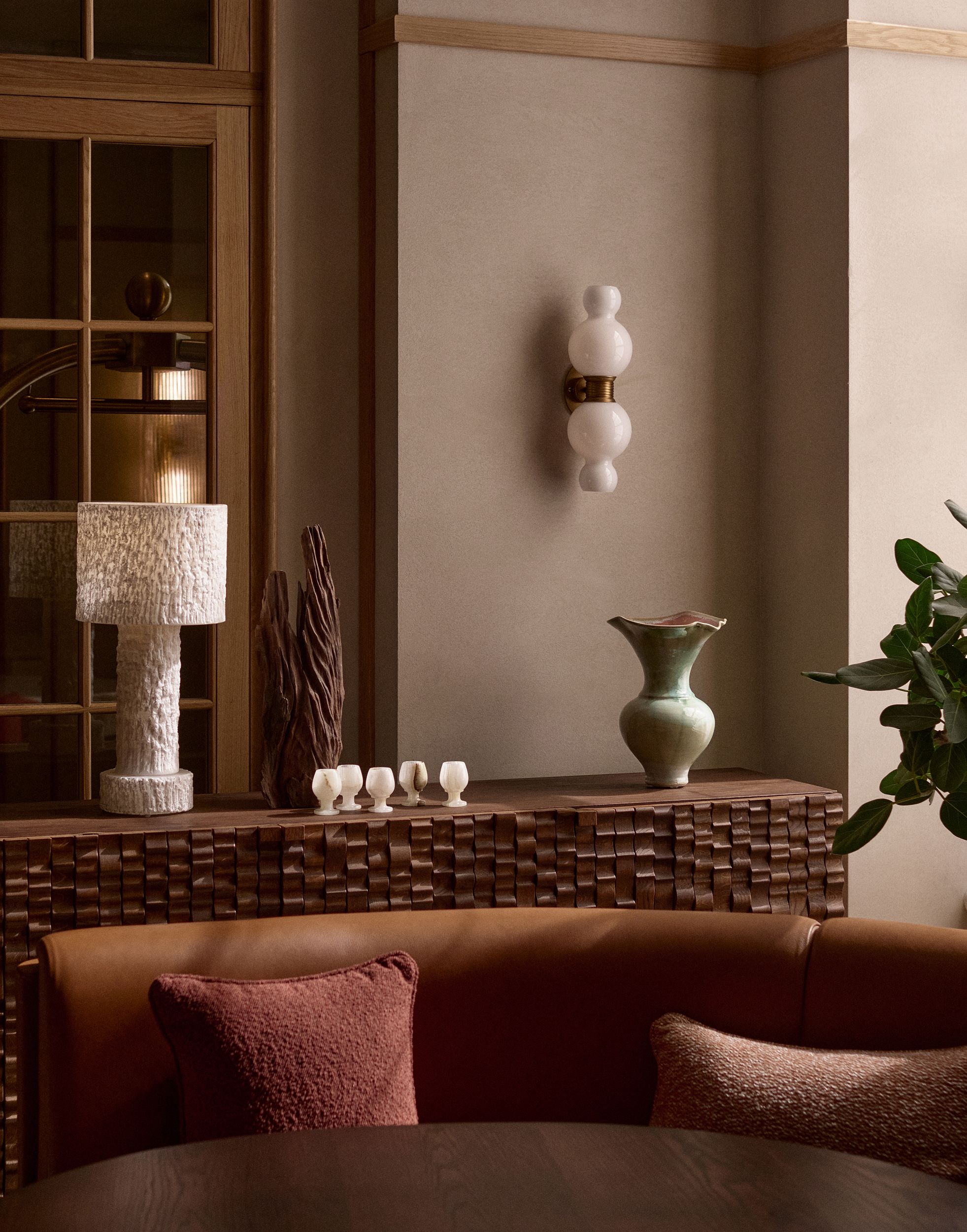 A chocolatey-shaded nook of a contemporary design hotel filled with textural creations like table lamps, shell egg cups, and aquamarine vases.