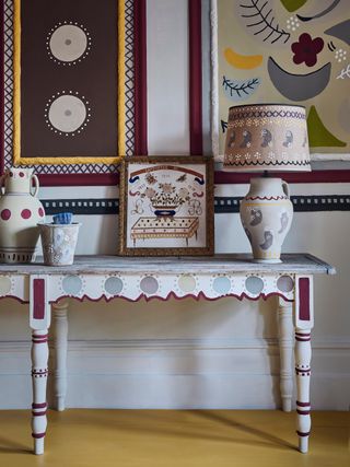 decorative hallway with handpainted console, painted/patterned wall panels and lamps