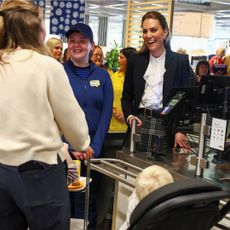 Princess Kate standing behind a cash register at IKEA serving a customer