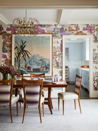 colorful dining room with retro table and chairs, illustrative wallpaper, large print, pastel blue kitchen in background