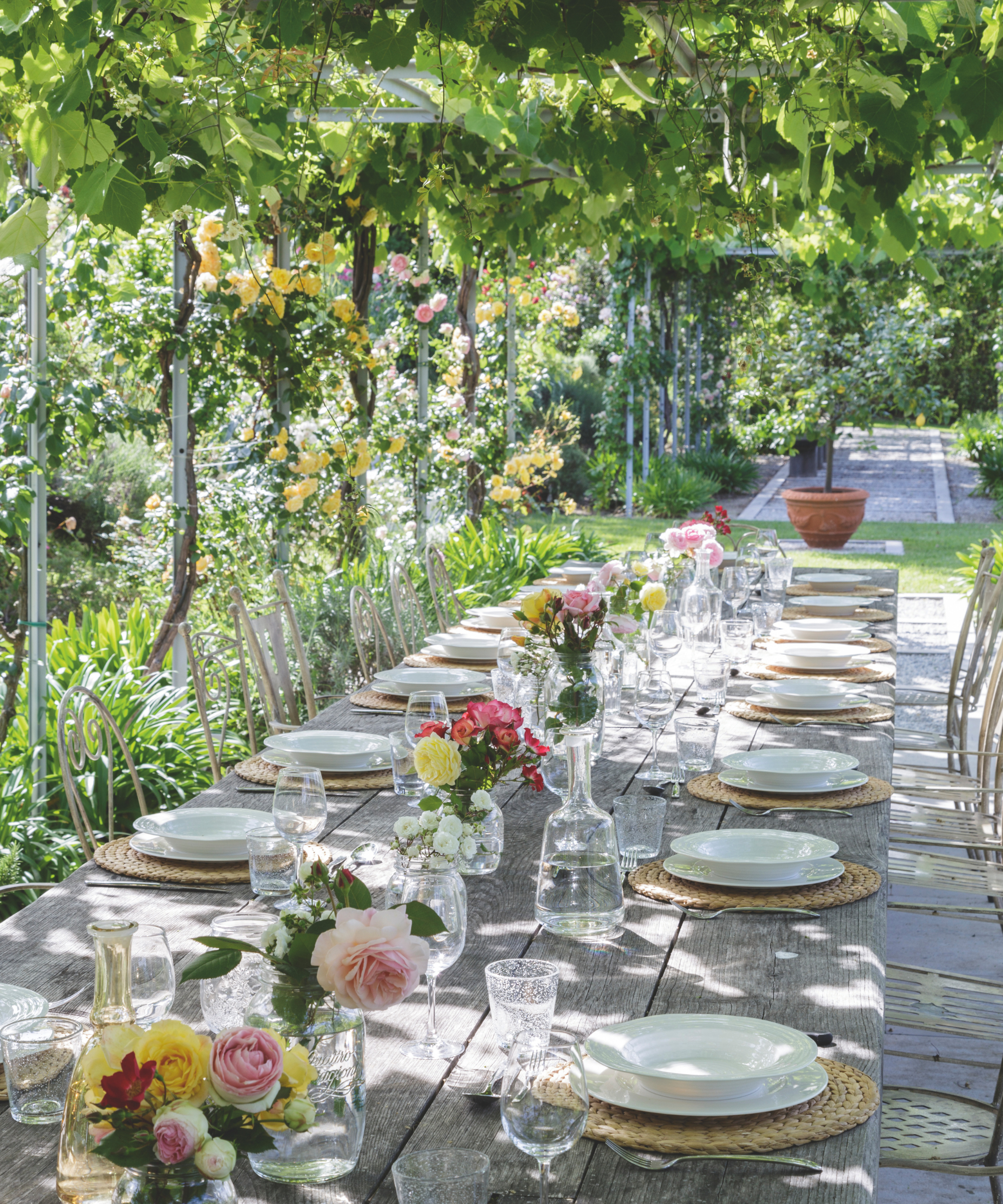 a dining table scene with plates, bowls, glassware, and bud vases filled with flowers