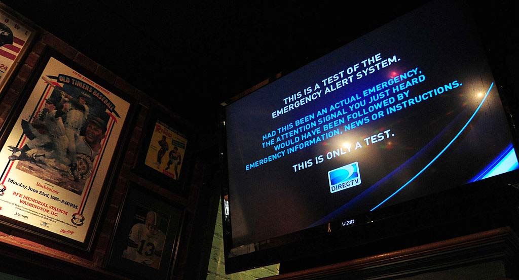 Bar patrons watch a test of the Emergency Alert System. 