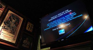 Bar patrons watch a test of the Emergency Alert System. 