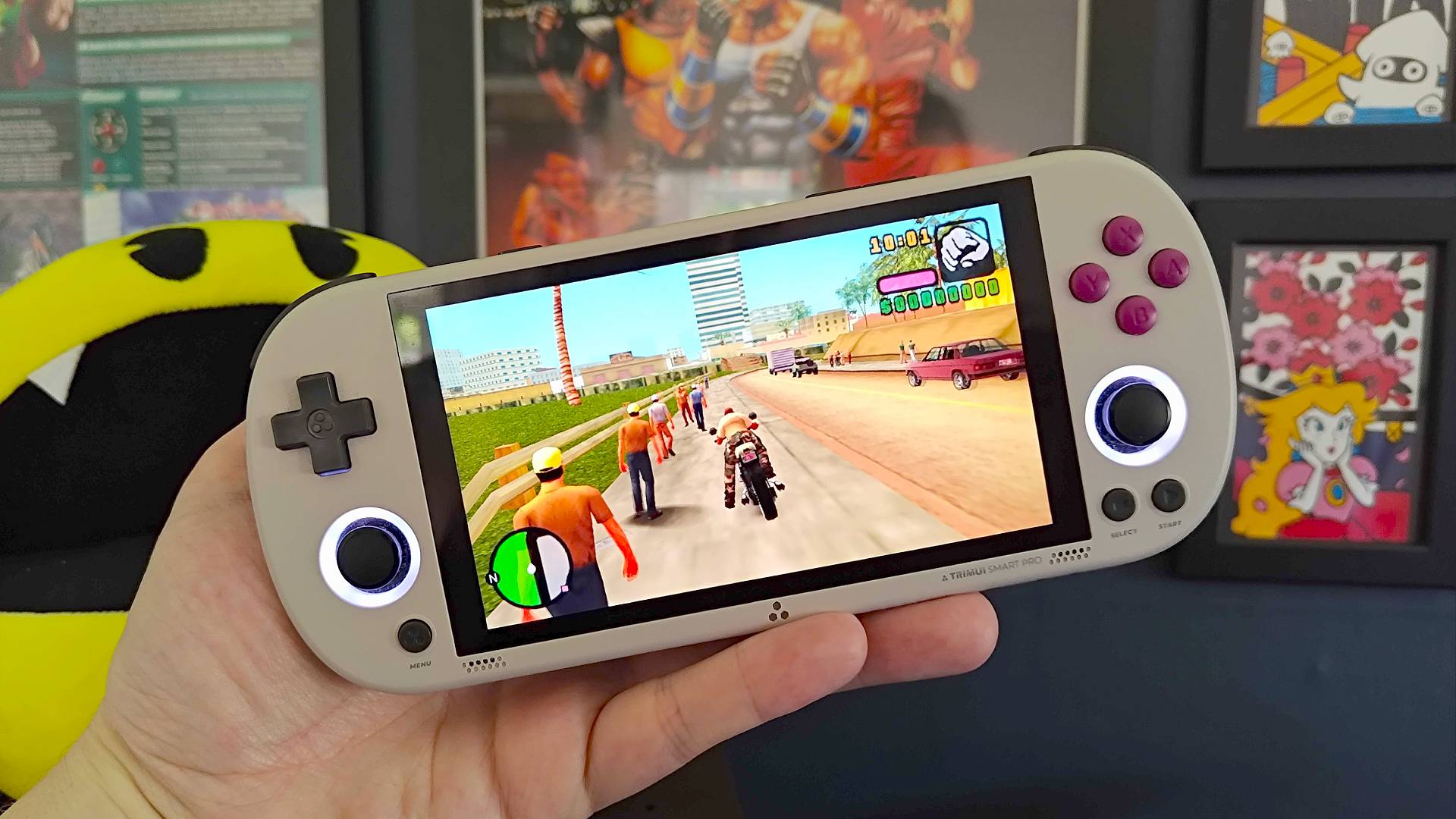 Hand holding Trimui Smart Pro handheld with GTA Vice City Stories gameplay on screen.