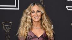 Sarah Jessica Parker is pictured with wavy hair and wearing a mauve and black dress whilst attending The Booker Prize 2025 Ceremony at Old Billingsgate on November 10, 2025 in London, England. 