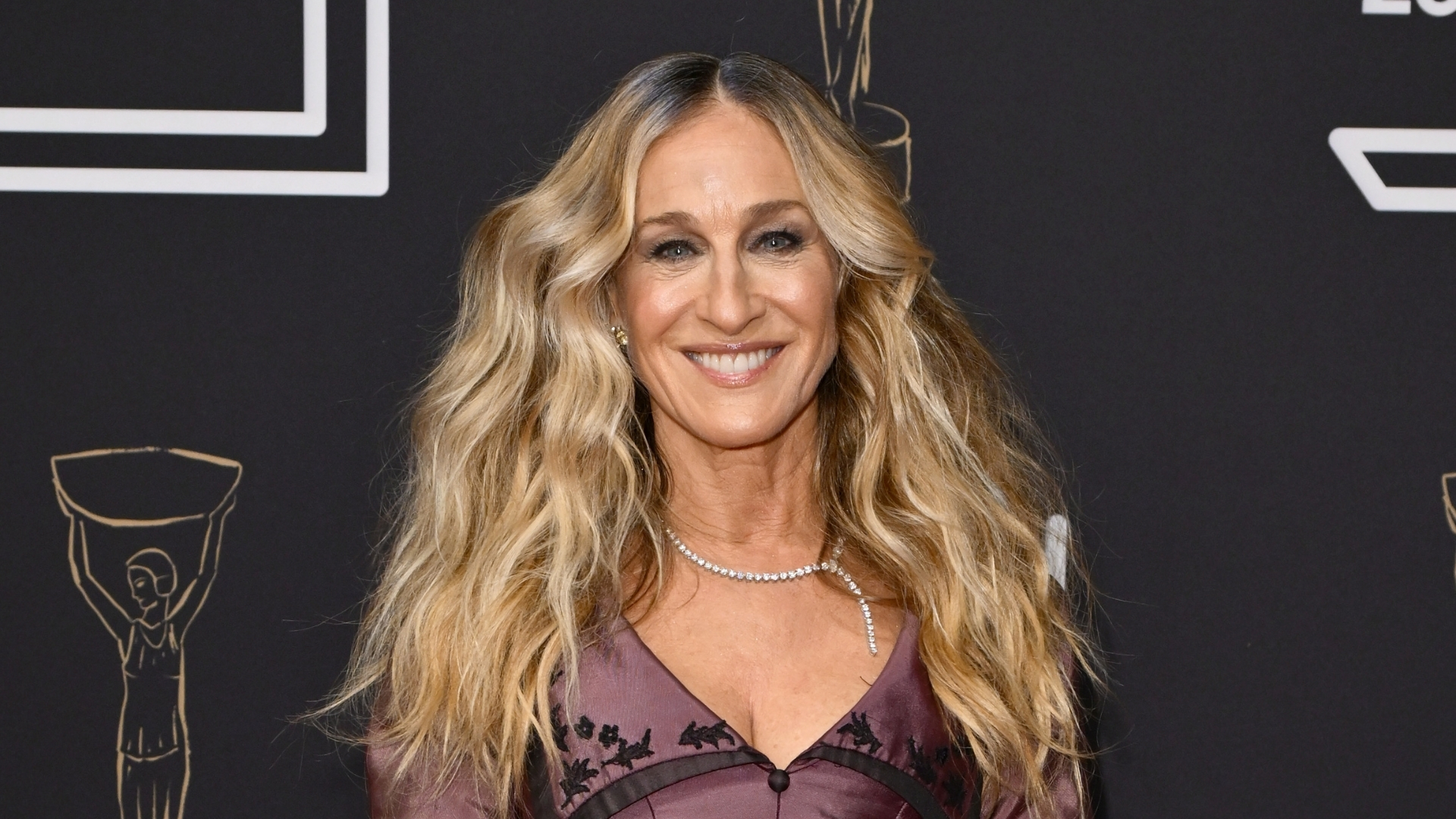 Sarah Jessica Parker is pictured with wavy hair and wearing a mauve and black dress whilst attending The Booker Prize 2025 Ceremony at Old Billingsgate on November 10, 2025 in London, England. 
