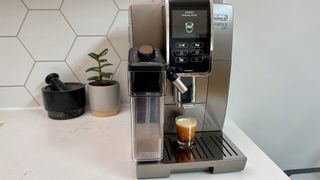 De’Longhi Dinamica Plus on a kitchen countertop being used to make an espresso