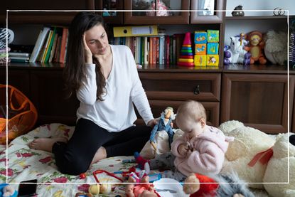 worried mum with a headache playing with her baby at home