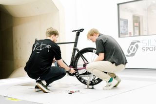 Silverstone sports engineering staff change a wheel of a bike in the wind tunnel