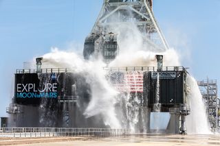 An enormous burst of water gushes over Pad 39B at NASA's Kennedy Space Center in Florida during a water flow test at its new mobile launcher. The launch tower will support the upcoming flights of NASA's new Space Launch System megarocket for the first Artemis moon mission. About 400,000 gallons of water poured onto the mobile launcher during this test, which took place on July 2, 2019.