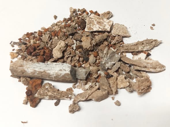 A pile of ashes and small stones against a white background.