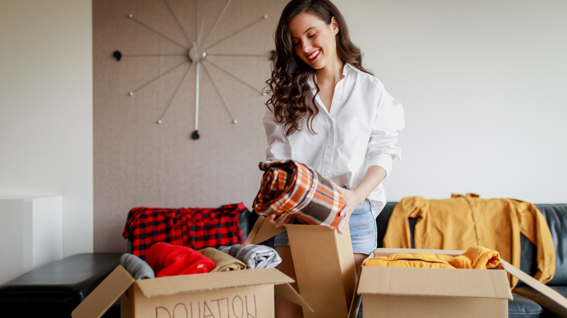 woman sorting items into cardboard donation boxes
