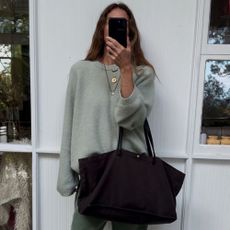 Angie wears a mint jumper, green jeans and carries brown tote bag