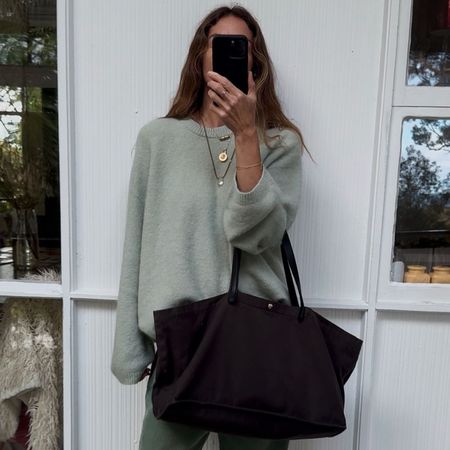 Angie wears a mint jumper, green jeans and carries brown tote bag