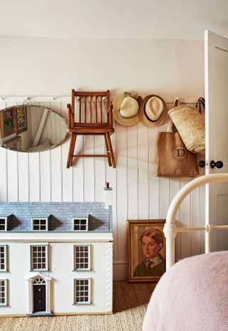 childs room with vintage dolls house and peg rail with chair, hats and mirror hanging and hats