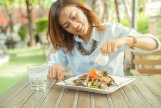 A woman pours dressing over the salad she's about to eat.