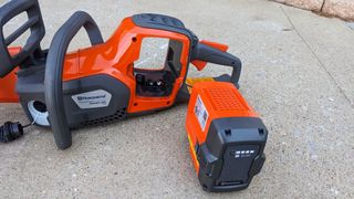 The battery fits into the middle of the body of the chainsaw. Once the battery is placed into the chainsaw, it’s much heavier than it is without the battery.