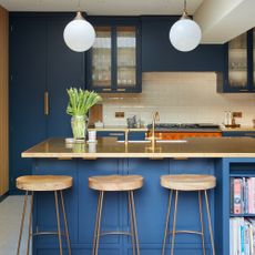 a kitchen island with breakfast bar and a row of three bar stools