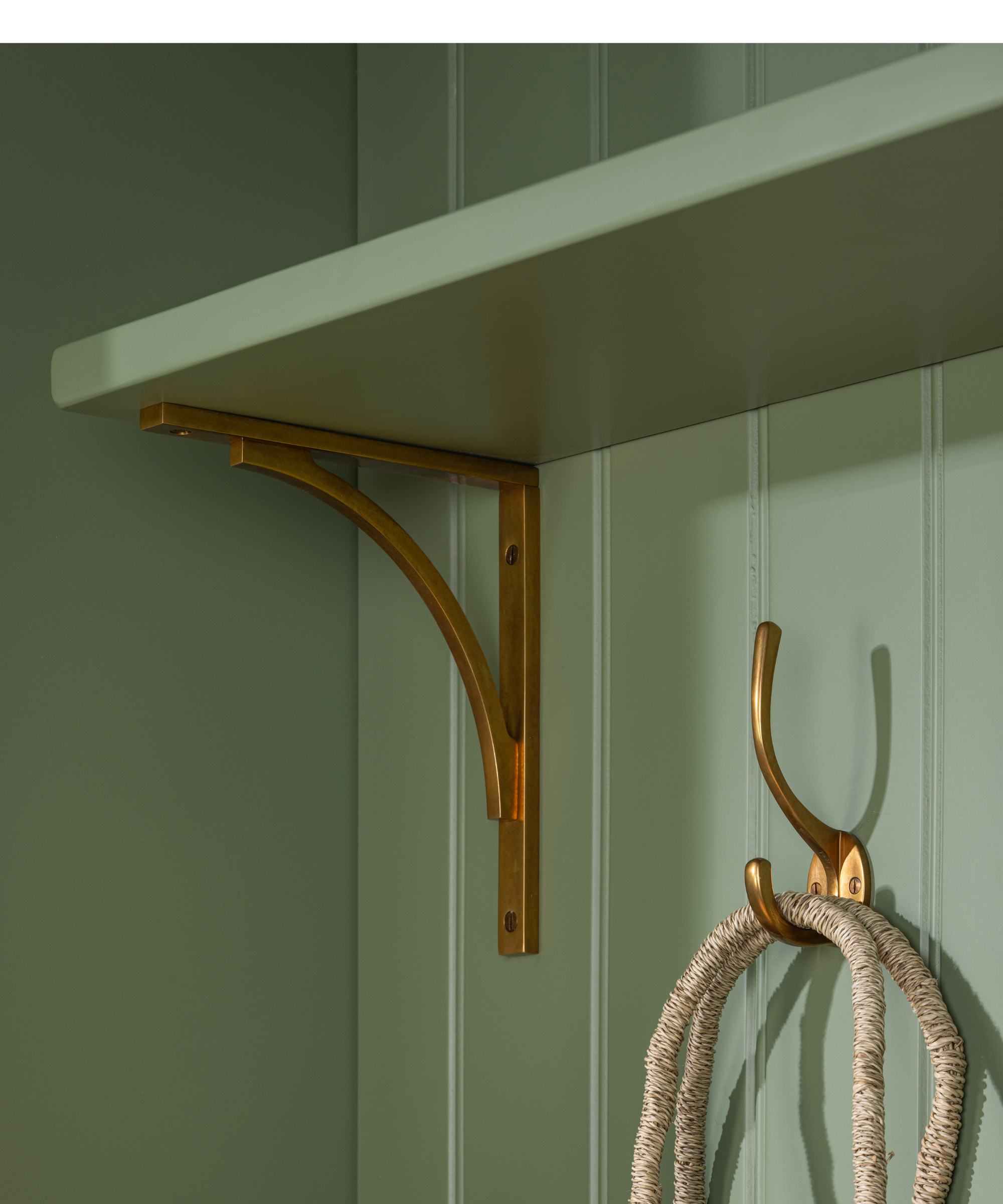 Close-up of green paneling with a shelf on a gold bracket