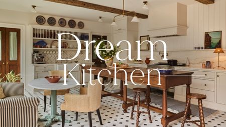 A war, layered kitchen with cream cabinets a wooden freestanding island, and a large plate rack at the top of a built-in hutch-style unit