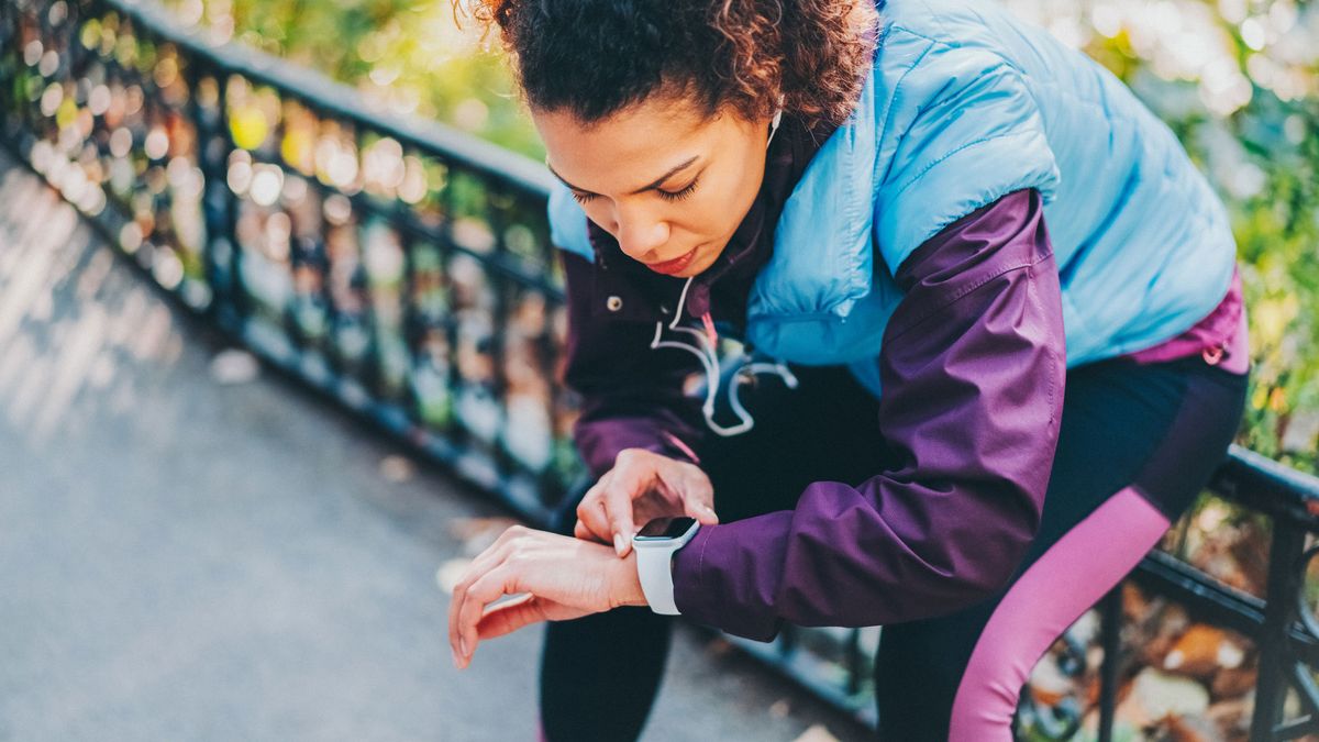 A woman checking her fitness tracker during workout in a park